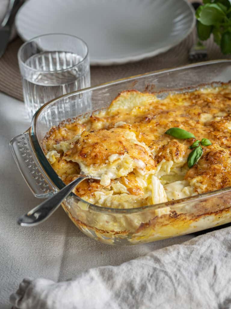 Kycklinggratäng med ost, potatis och grönsaker i en ugnsform.