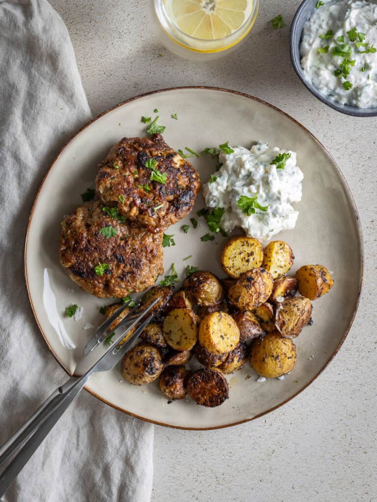 Laxburgare med potatismos och gräddfil på tallrik.