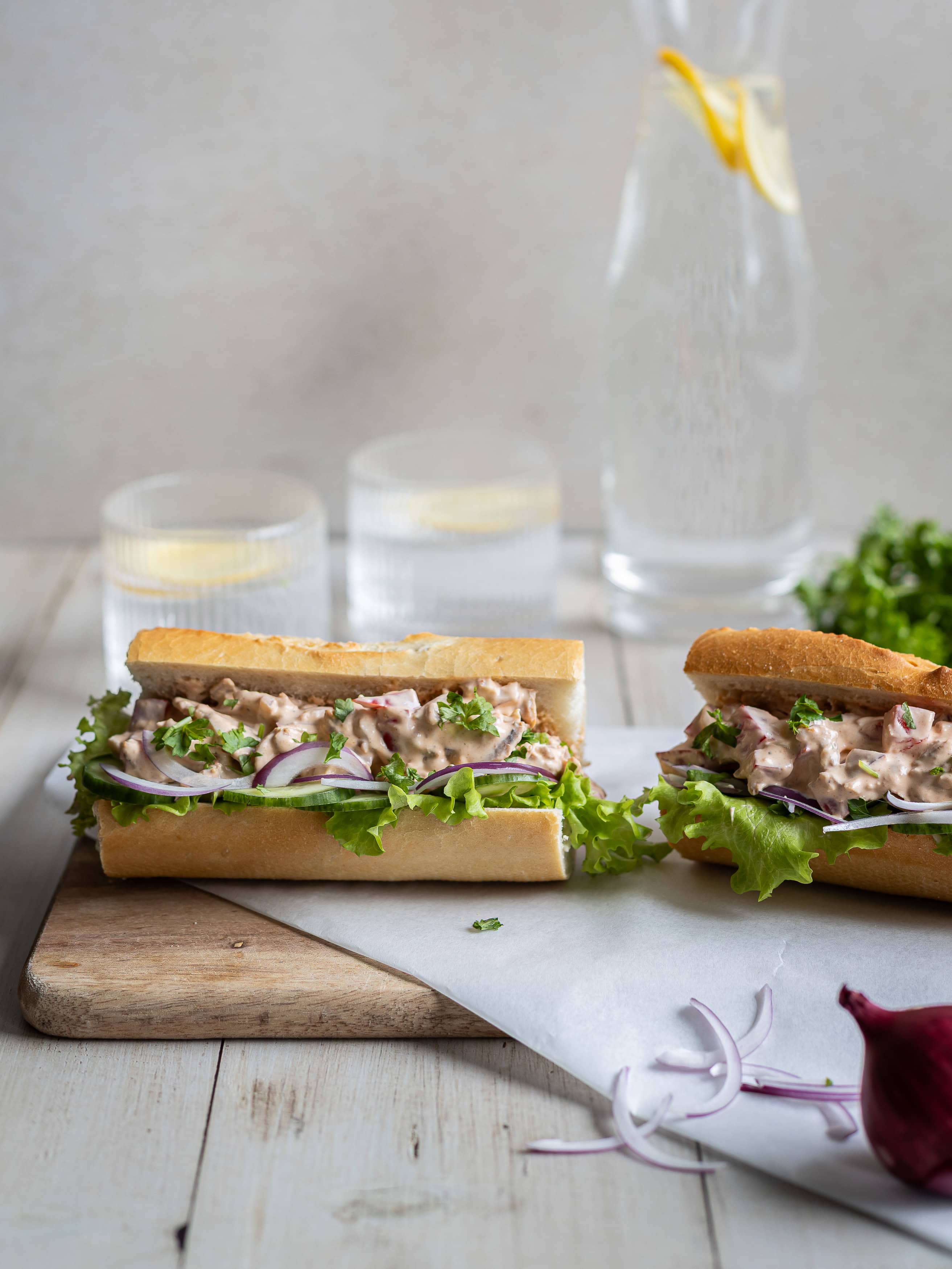 Smörgås med fiskröra, sallad och bröd på träskärbräda.