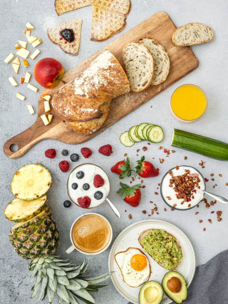 Frukostbord med bröd, frukt, yoghurt och ägg.