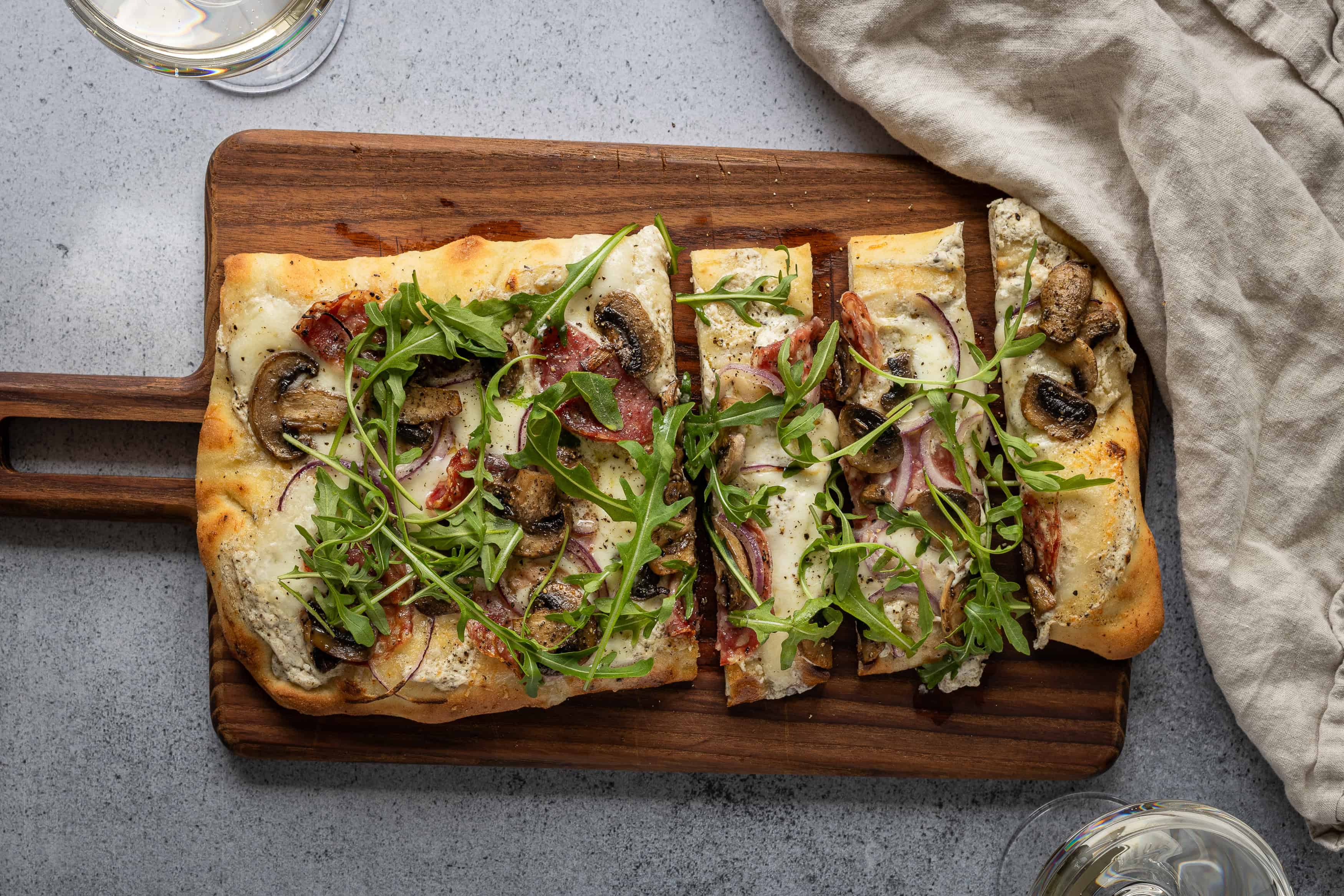 Pizza med svamp, ost och ruccola på träbricka.