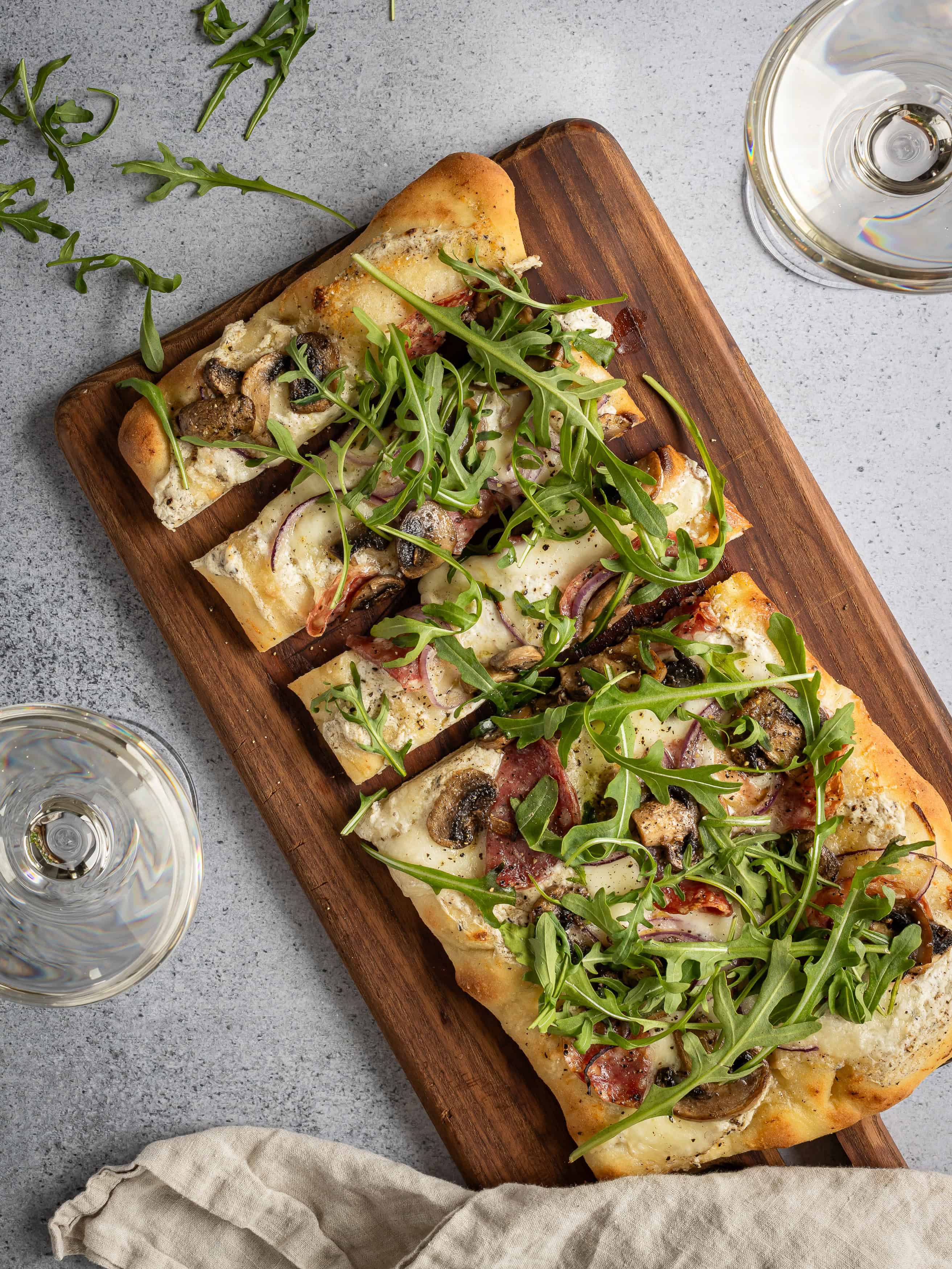 Vegetarisk pizza med svamp, tomat, ost och ruccola på träskärbräda.