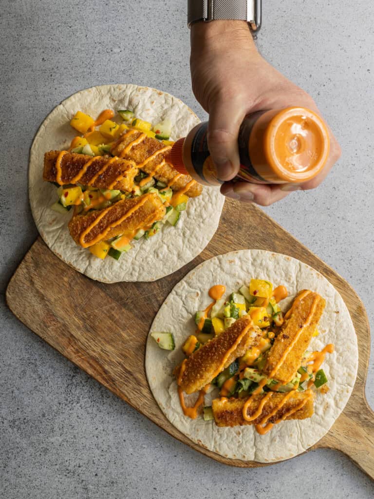 Kycklingtacos med grönsaker och sås på tortillabröd.