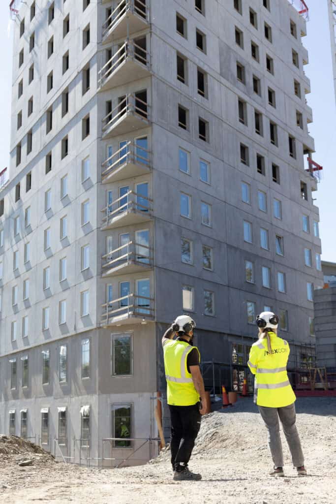 Byggnadsarbetare i säkerhetsutrustning granskar ett pågående byggprojekt.