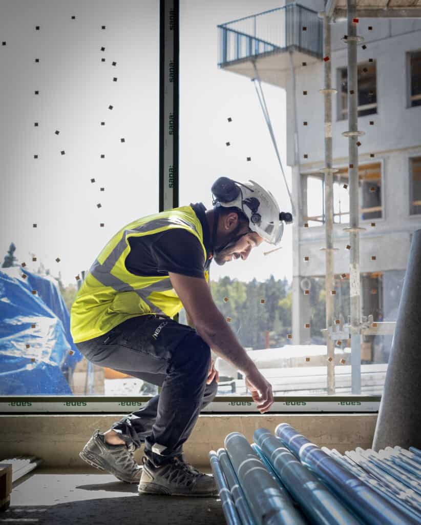 Byggarbetare i säkerhetsutrustning på byggarbetsplats i Uppsala.