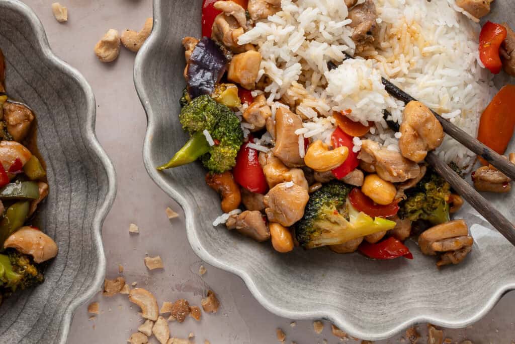 Kycklingwok med broccoli, paprika och cashewnötter på en grå tallrik.