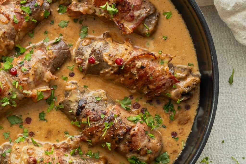 Kycklinggryta i krämig sås med örter och kryddor, serveras i en svart gryta.